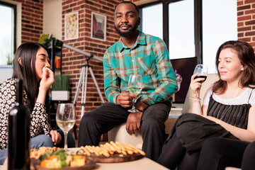 African american young adult man smiling, happy portrait, having fun, enjoying at multiculturally different friends, mates, partners home, house, apartment wine toasting.