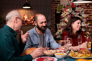 Happy family celebrating christmas, people talking at festive dinner table, eating traditional winter holiday food, chatting. Xmas eve celebration with parents at home party