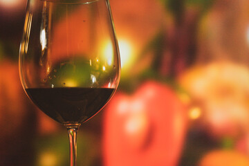 a crystal glass with wine on some stones and a bottle of wine on a trunk table with colored lights and glamor to share a pleasant moment with a lot of flavor and pleasure