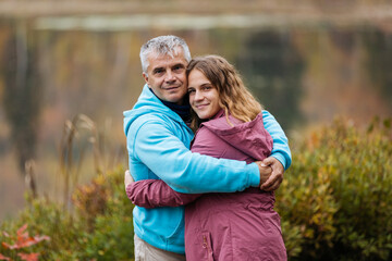 Middle aged father and daughter hug each other outdoors