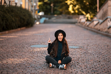 Young woman sitting at city show finger up, new idea