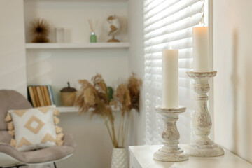 Beautiful wooden candlesticks on white table in room, space for text