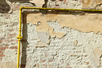 Yellow gas pipe on old brick wall outdoors