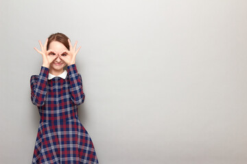 Portrait of happy young woman showing okay gestures near her eyes
