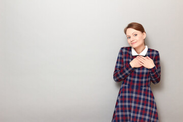 Portrait of happy woman holding hands on chest and thanking somebody