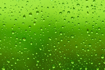 Plakat Water drops on glass surface over blurry colored background