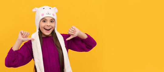 amazed kid in earflap hat on yellow background. Banner of christmas child girl, studio kid winter portrait with copy space.