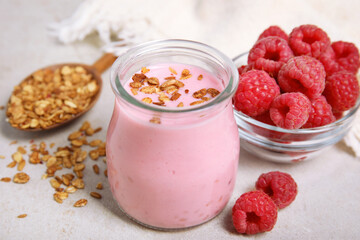 Tasty raspberry smoothie with granola in glass jar and fresh berries on light table, closeup