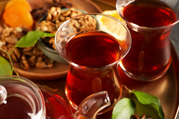 Tray with glasses of traditional Turkish tea, pot and ingredients, closeup