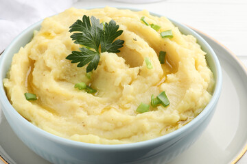 Bowl of tasty mashed potatoes with parsley and green onion on table, closeup