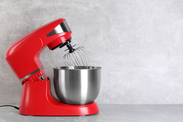 Modern red stand mixer on light gray marble table, space for text
