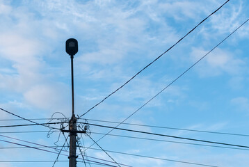 Lamppost with bunch of wires in mess against cloudy blue sky