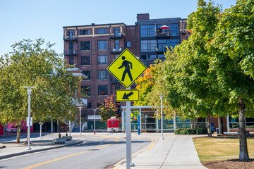 a yellow and blue street sign with a human figure walking surrounded by red brick apartments and autumn colored trees and lush green trees at World's Fair park in Knoxville Tennessee USA - obrazy, fototapety, plakaty