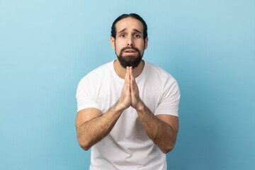 Please, I'm begging forgive. Portrait of upset worried man with beard wearing white T-shirt looking...