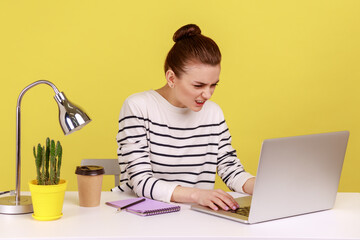Portrait of woman office manager sitting in front of laptop and typing on keyboard, looking at...