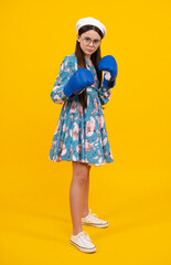 Teenage fun boxer girl in boxing gloves on yellow isolated background. Funny girl boxer in fun gloves boxing, studio shot on yellow.