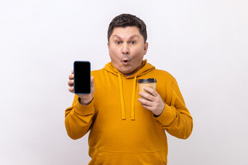 Portrait of astonished surprised man of middle age holding smart phone with blank screen and...