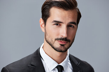 Portrait of a business man in a stylish suit with tie beautiful face on a gray isolated background. Business concept young businessman startup copy space