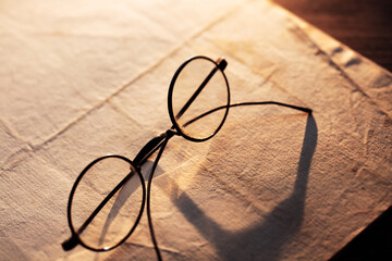Vintage eyeglasses on an old paper.  Low-key incandescent lighting. Shallow depth of field.