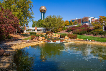 a gorgeous autumn landscape at World's Fair park with a flowing river with green water rushing over...