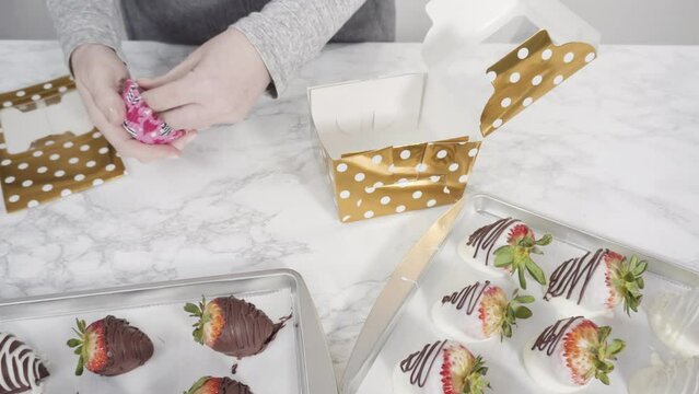 Step by step. Packaging chocolate dipped strawberries into a paper box for a gift.
