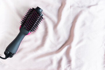 Electric blowout brush hair dryer on a pink background