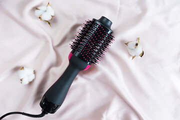 Electric blowout brush hair dryer on a pink background
