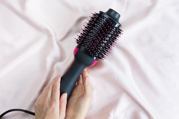 Electric blowout brush hair dryer on a pink background