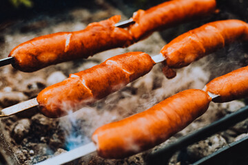 Sausages close-up on the grill on fire, against the background of smoke. Meat and snacks, food and fast food
