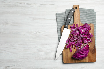 Tasty fresh shredded red cabbage and knife on white wooden table, flat lay. Space for text