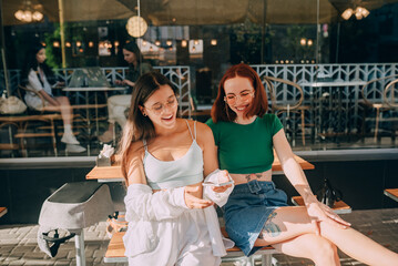 Girls using smartphones while sitting at the cafe outdoors