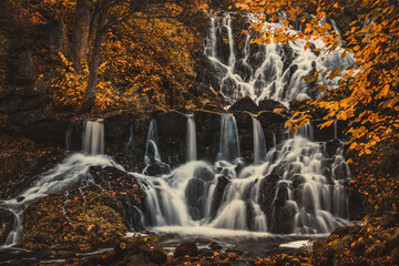 Fototapeta na wymiar Beautiful waterfall in autumn forest in Jonkoping, Sweden. Long exposure.
