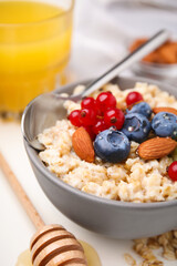 Oatmeal served with berries. almonds and mint on white table, closeup