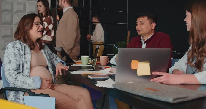 Happy pregnant woman talks to two HR managers applying for job at office table business meeting interview slow motion.