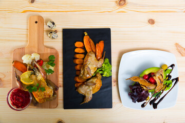 Close up of delicious fried partridge and quail with avocado, greens and tomatoes
