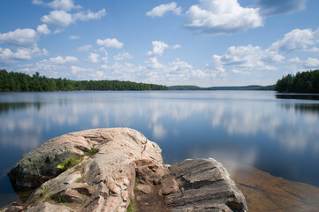 Long Exposure on Smoke lake in Algonquin Provincial Park, Muskoka Ontario Canada. Sky clouds are reflecting on the calm waters of the lake.