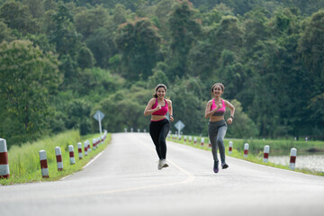 Two Asian women running in the park and smiling.
