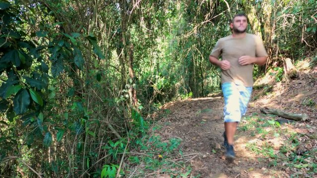 Man running on the trail in the middle of the woods trying to lose weight. Running towards the camera. Fitness healthy lifestyle. Jogging on the trail, filmed in real-time camera. 4k video, 29.97 fps