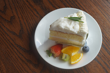 top view white Coconut cake and strawberry, kiwi, orange slices, one blueberry on a white plate, on a wooden table, dessert, food, nature, health