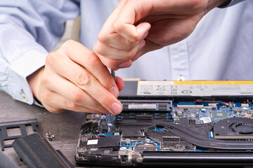 Notebook repair. Man disassembles a laptop. Removes the keyboard. Computer service and repair concept. Laptop disassembling in repair shop, close-up.