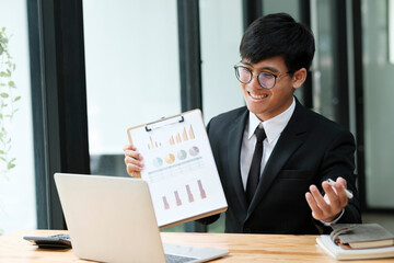 Businessman having video call with client and holding graph paper.