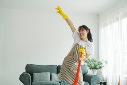 Young woman having fun while cleaning home.