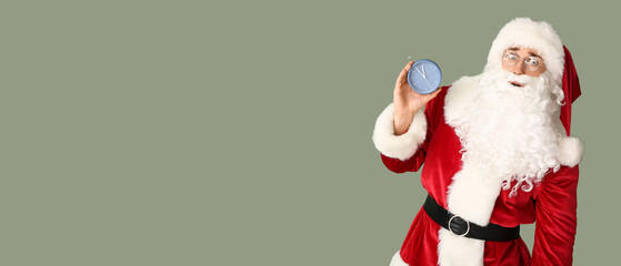 Surprised young man in Santa costume holding alarm clock on color background with space for text. Christmas countdown concept