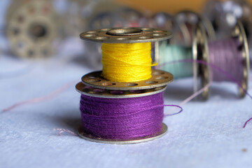 Multicolored threads on the bobbin from the sewing machine on a blurred background from the other...
