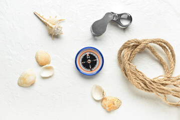 Vintage compass, magnifier, rope and seashells on light background