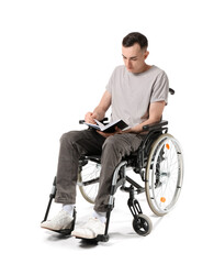 Young man in wheelchair reading book isolated on white