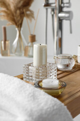 Holders with candles on wooden bathtub tray, closeup