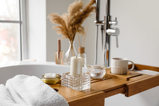 Wooden bathtub tray with candles and cup of tea
