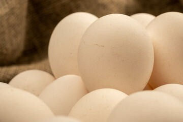 White chicken eggs in a cardboard box on the table. Close-up, selective focus