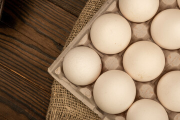 White chicken eggs in a cardboard box on the table. Close-up, selective focus.